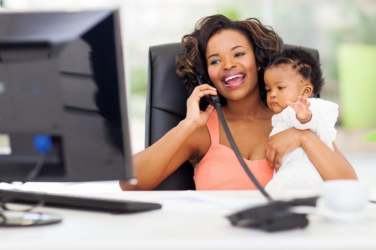 businesswoman talking on landline phone while holding baby