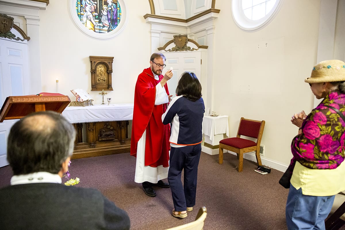 <em>Gribowich gives communion to worshippers during a weekday mass at the St. Joseph the Worker church. (UC Berkeley photo by Brittany Hosea-Small)</em>