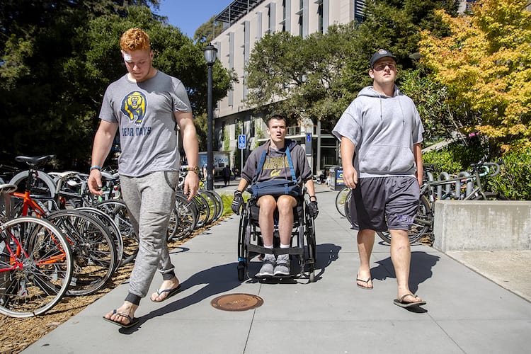 <em>Jack Iscaro (left) and Brian Joyce, two of Paylor’s rugby teammates, escort him to physical therapy at the Simpson Center for Student-Athlete High Performance. (UC Berkeley photo by Brittany Hosea-Small)</em>