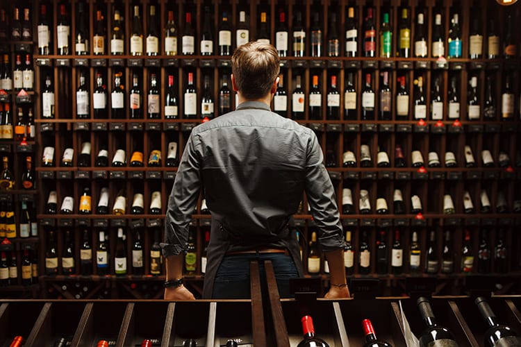 A bartender looks at bottles in a wine cellar