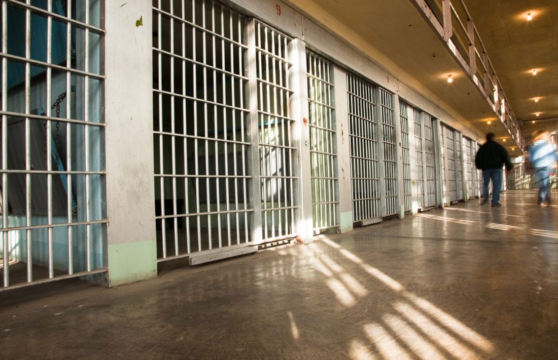 Two people walking down a prison corridor