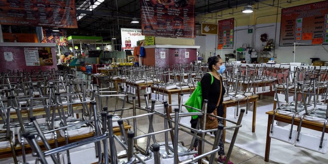 A woman in a mask walks through an empty market