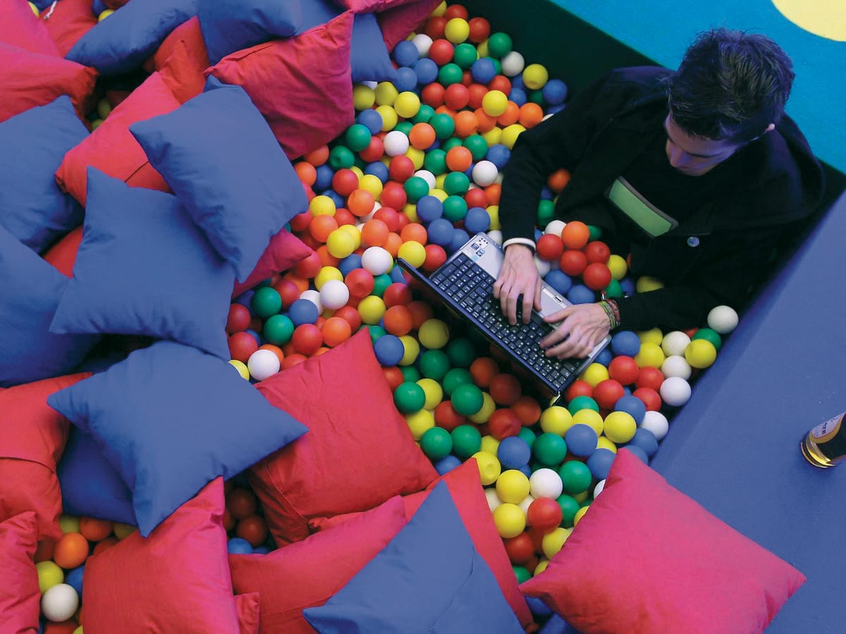 Worker sitting in a pool of colorful balls.