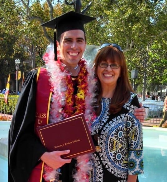 student in cap and gown, posing with woman