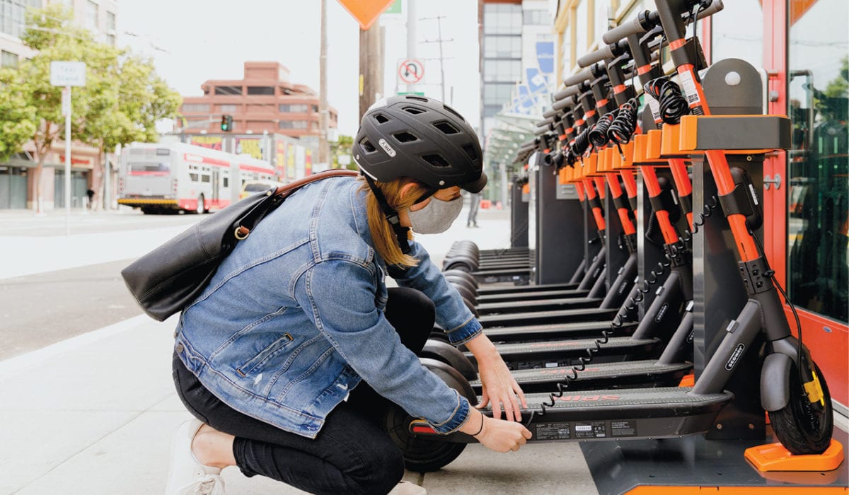 Woman in a helmet docking a Spin e-scooter.