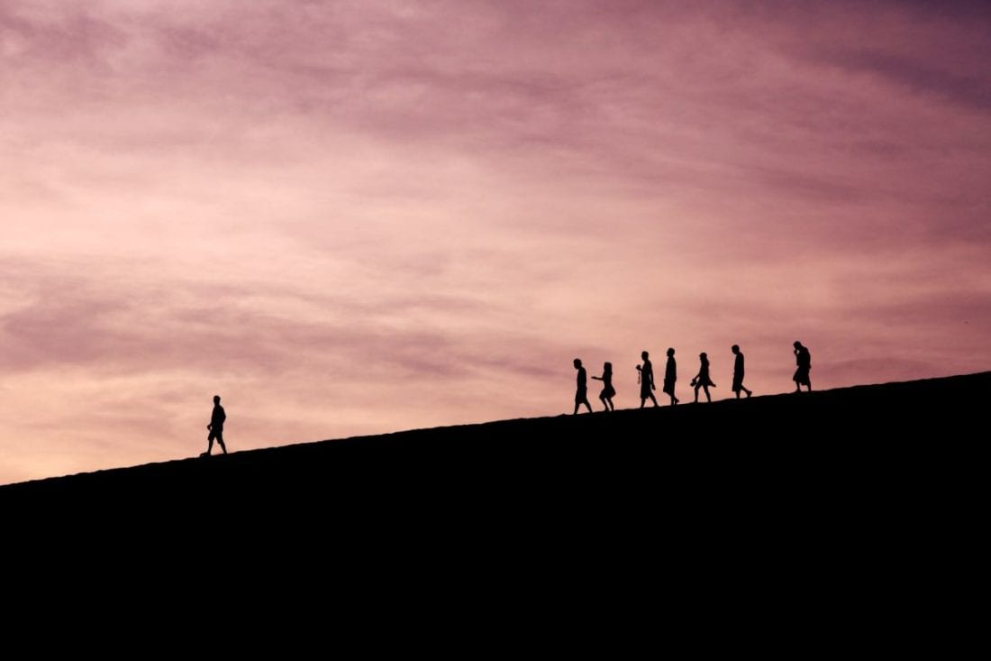 A silhouetted figure leads a group