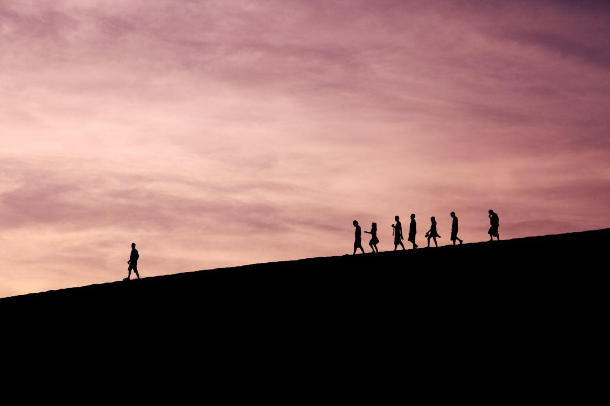 A silhouetted figure leads a group