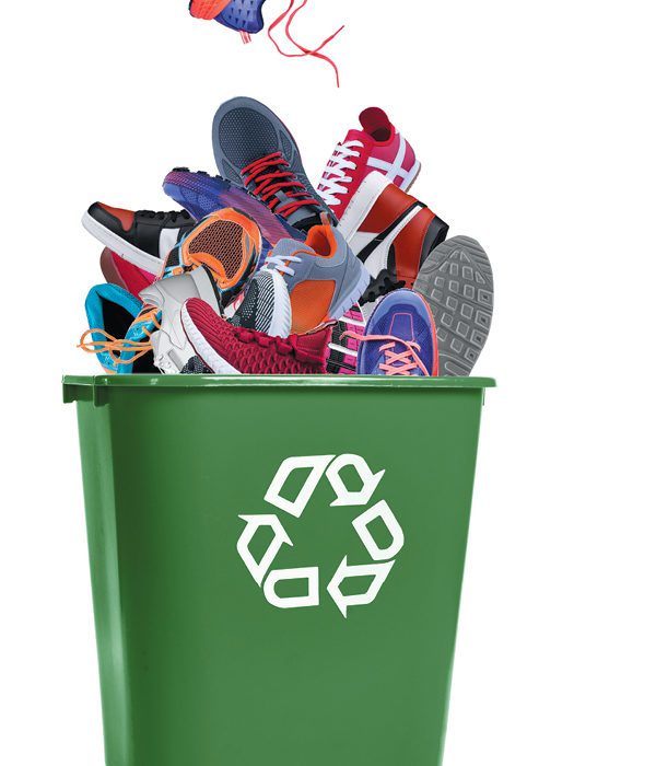 Green recycling bin overflowing with mis-matched sneakers.