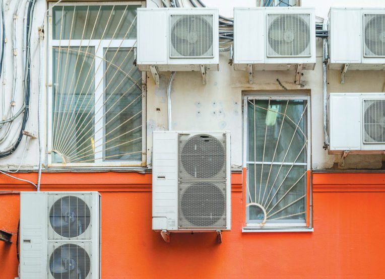 Close-up of the back of an apartment building with numerous air conditioning units.