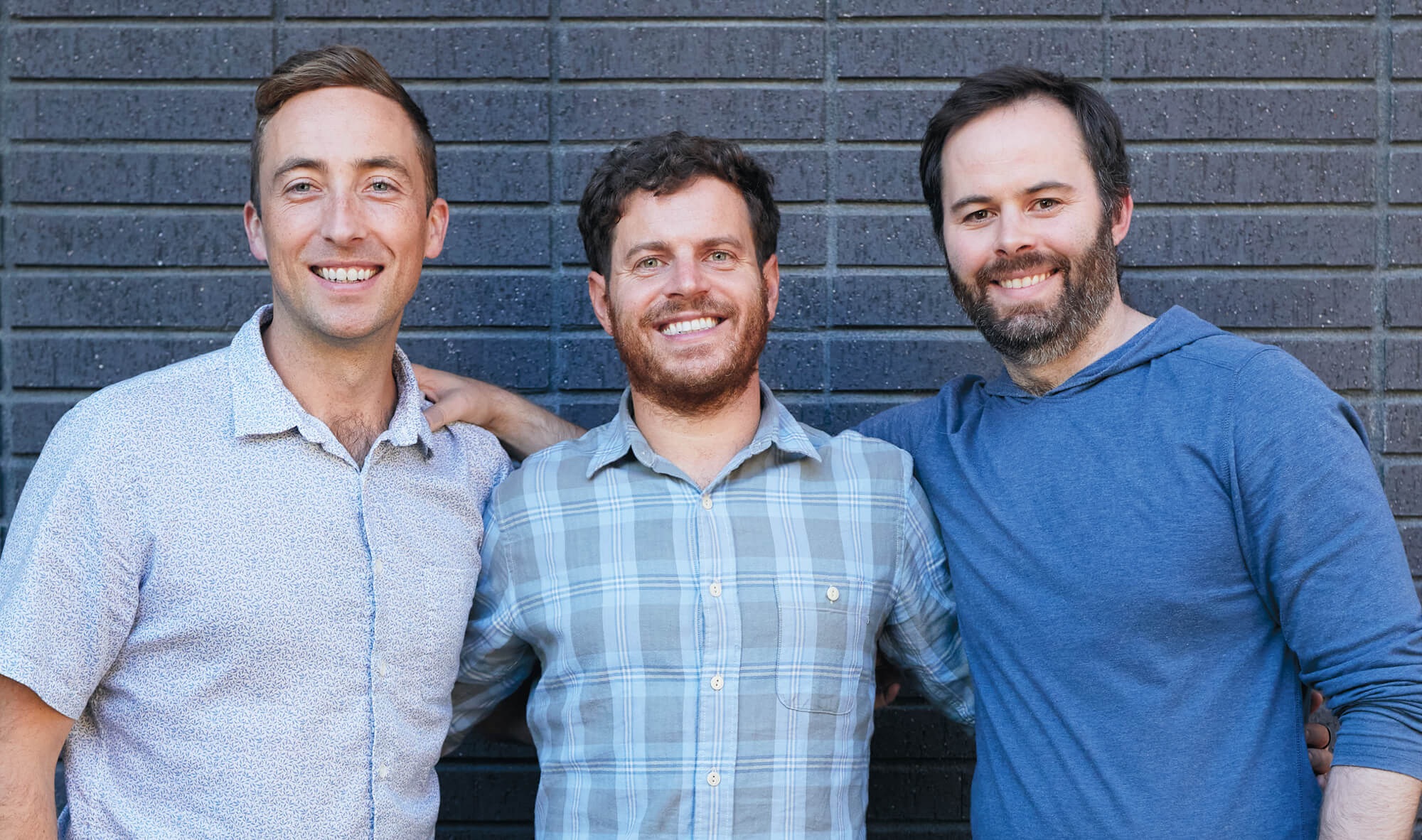 Chad Brinton, Chip Malt, and Matt Gunderson, all MBA 15, standing in front of a blue brick wall.