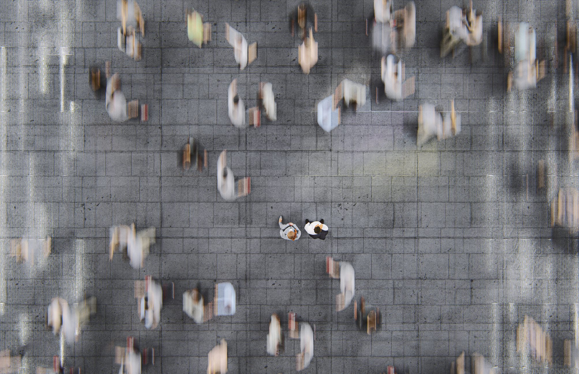 Intentionally blurred image shows a fast-moving crowd of commuters with two people standing in the middle