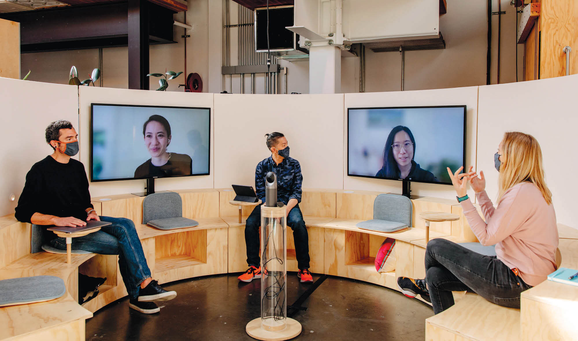 Five people in a semi-circle. Two of them appear virtually, on screens.