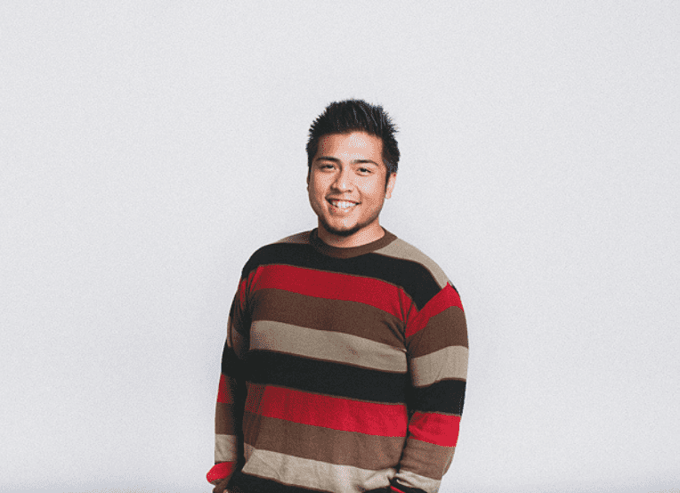 Filipino American man with short black hair wearing a striped sweater