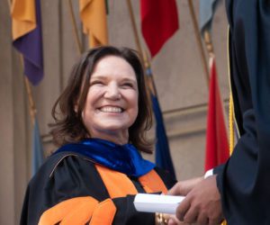 Dean Ann Harrison hands a student an MBA diploma