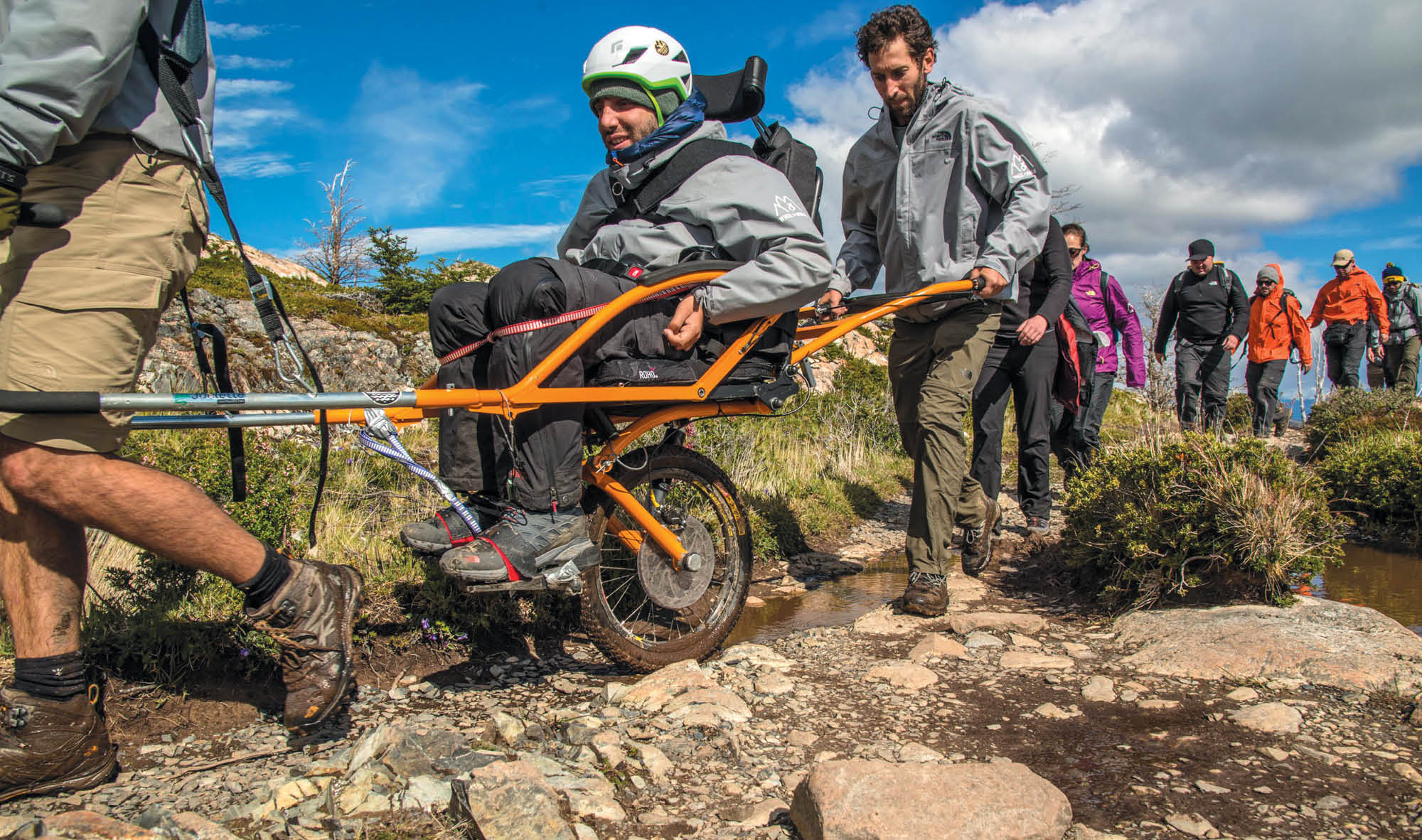 Man in a specialized wheelchair made for trekking through rough terrain.