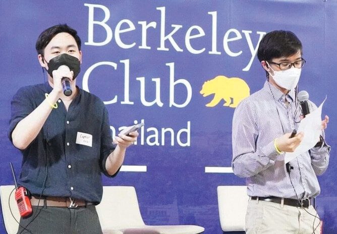 Two men in front of a sign that reads Berkeley Club of Thailand.
