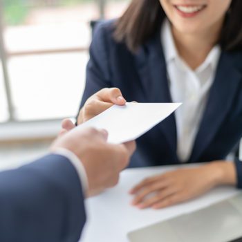 Young Asian business woman in blue suit receiving an envelope with a salary offer