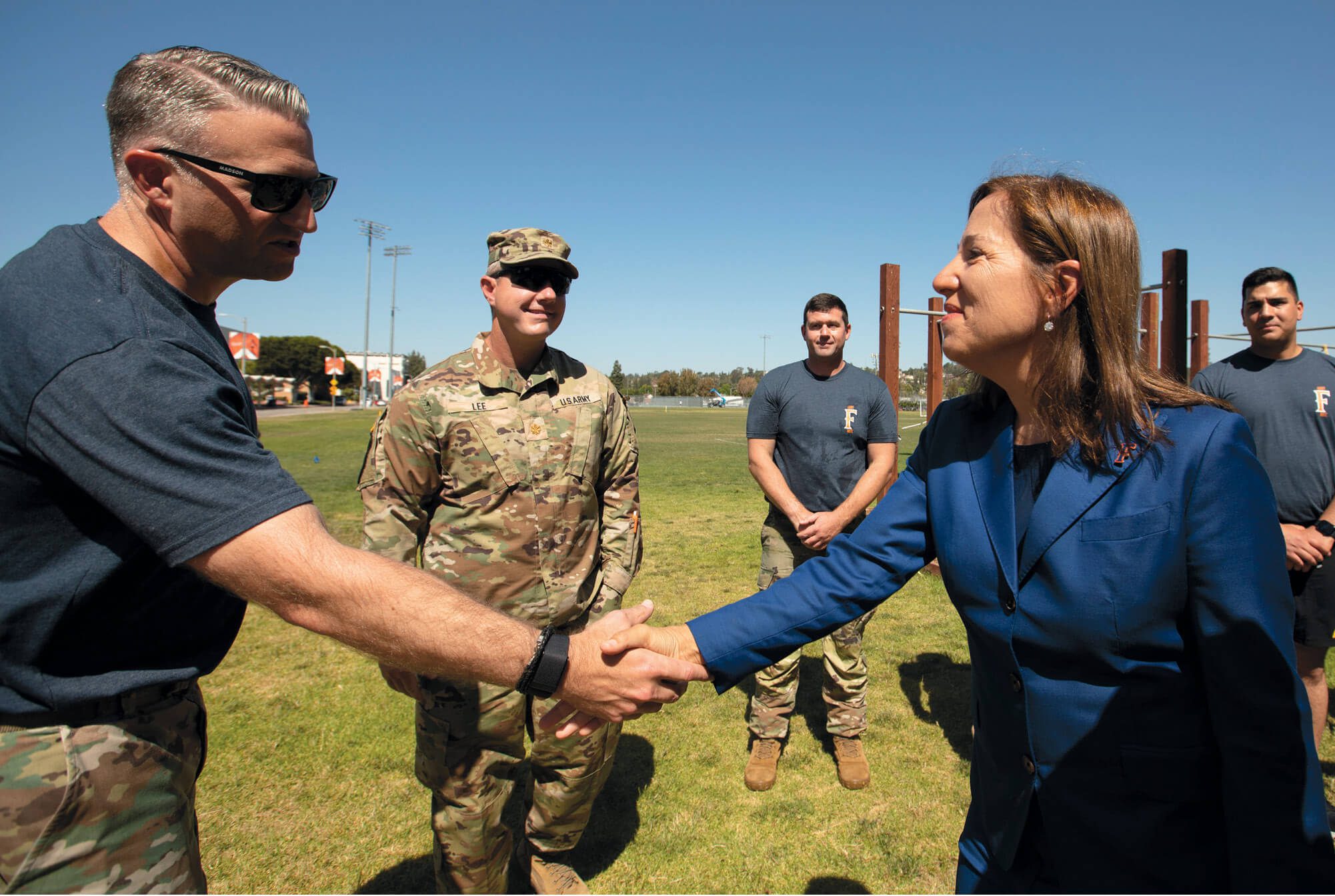 Woman shaking a veteran's hand while three other veterans look on.