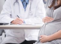 Portrait of pregnant woman with doctor in clinic