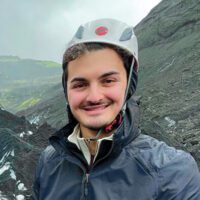 Matthew Taksa wearing a helmet in front of a mountain.