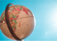 A Desk Globe in the left forefront of the image. Backdrop is clear blue sky.