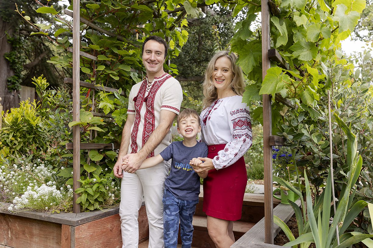 A man, woman, and young boy pose for a photo in a garden.