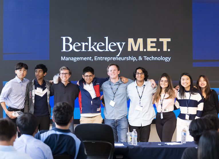 A group of high school students with arms around each other in front of a Berkeley MET sign