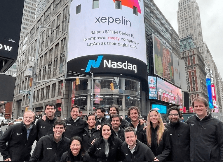 A group of people standing in front of a Nasdaq billboard