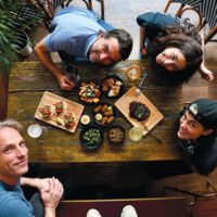 Overhead shot of four people sitting at a table with food in front of them.
