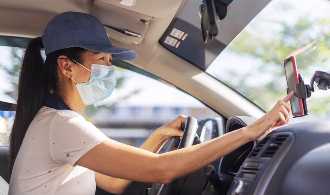 An Uber driver wearing a face mask and hat.