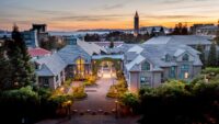 Photo shows the Berkeley campus at sunset with a clock tower on the horizon