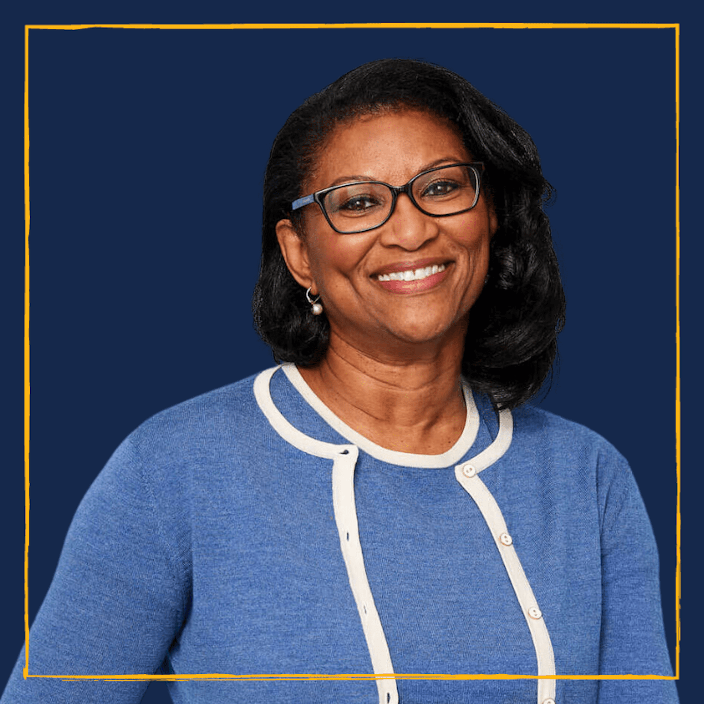 Photo of Panamanian- American Alumna. Brown Skin, Dark hair, smiling, wearing glasses and a blue and white top against Berkeley Blue background.