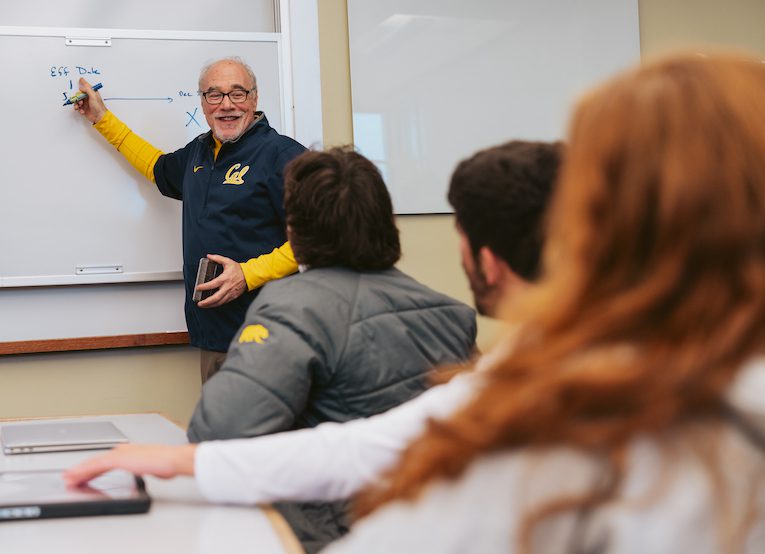 professor in Blue Cal shirt teaching at whiteboard