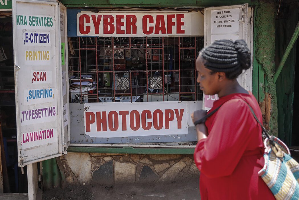 A woman wearing red walks past an internet cafe in the Kibera neighborhood of Nairobi, Kenya.