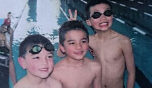 three boys standing in a swimming pool