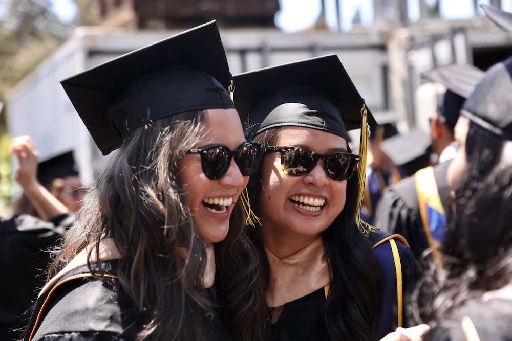 two women grads in cap and gown smiling