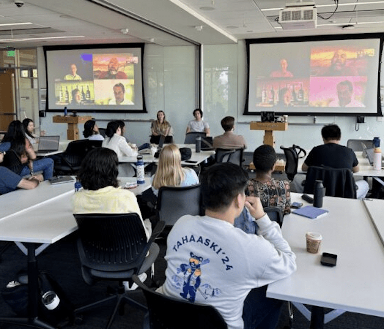 Photo of IBD students looking at two jumbo projectors where IBD Alumni Share How IBD Has Influenced Their Careers via Zoom or a similar platform.