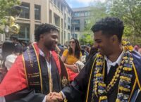 two men in graduation regalia shaking hands