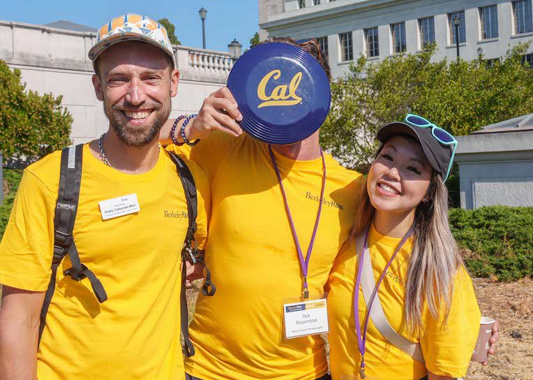 three students, one holding a cal frisby in front of his face.