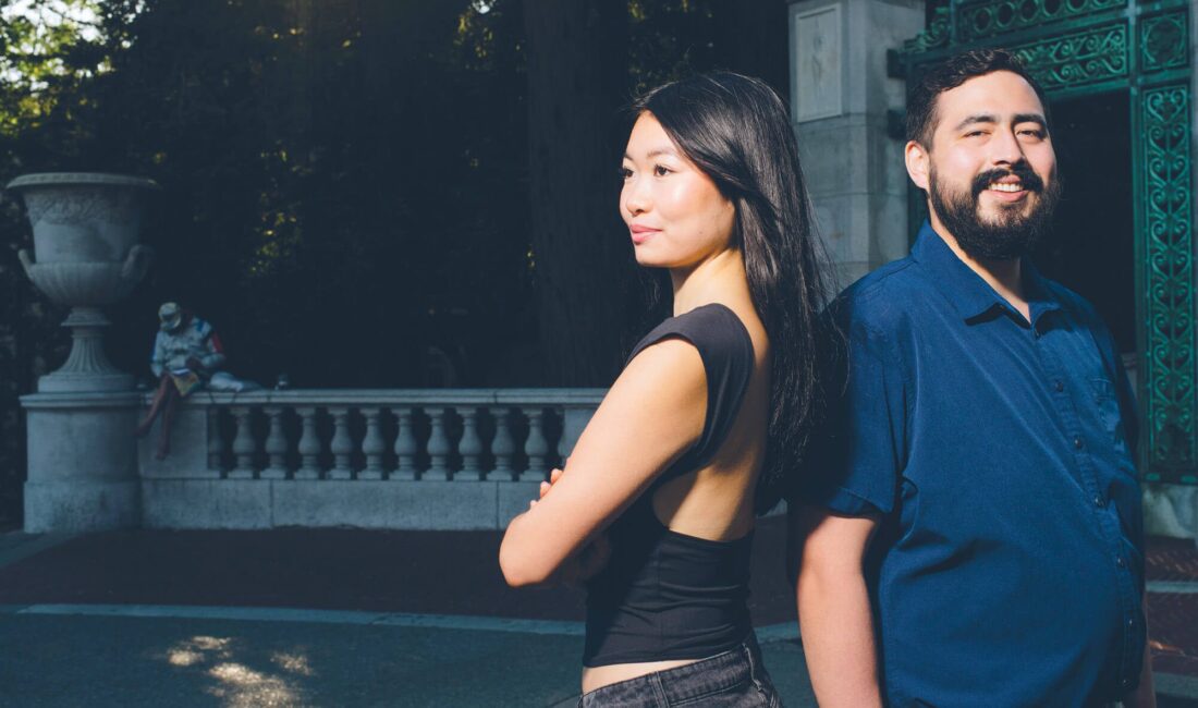 A young woman and man standing back to back.