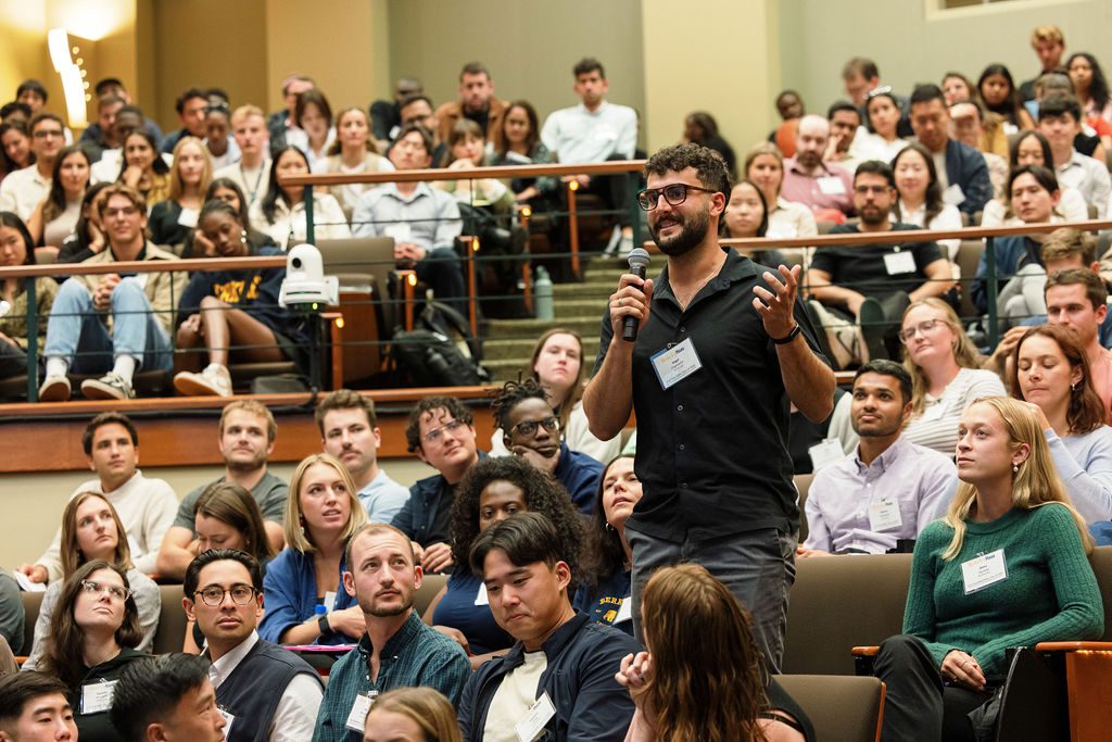 man wearing glasses asking a question during orientation