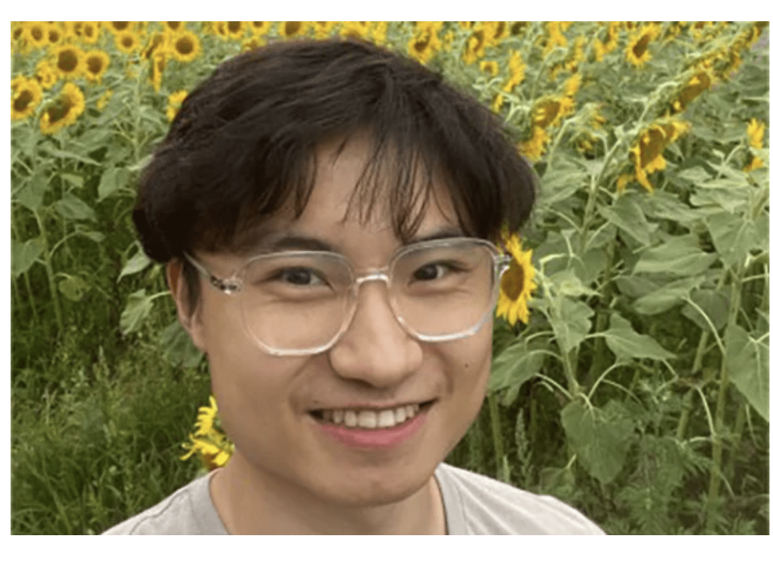 Photo of Xiao Tian (Jason) Zhou, MFE 25 in front of large sunflowers.