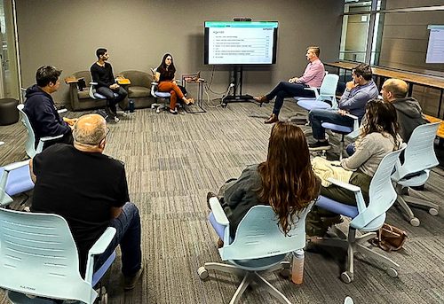 a group sitting in a circle with a white board talking