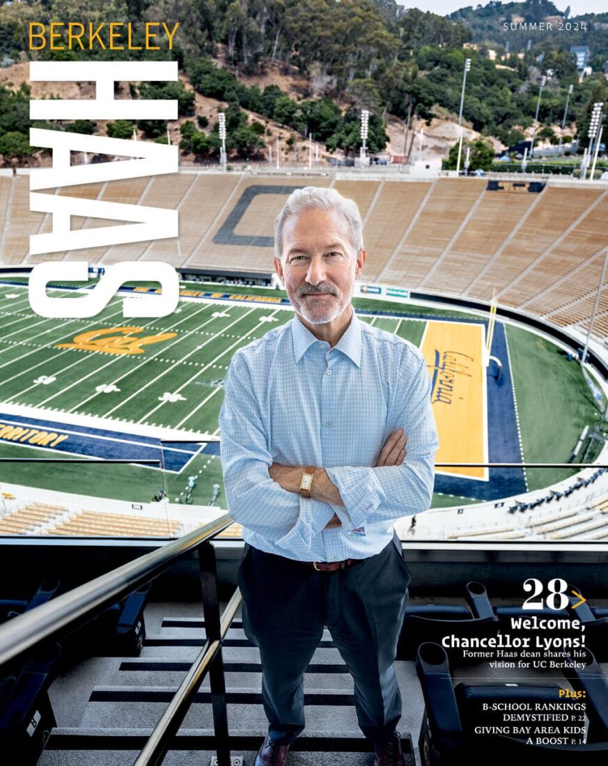 Cover of summer 2024 Berkeley Haas magazine showing a man with arms folded standing high up in a stadium with a football field behind him. The word Cal appears in the center of the field and California is written in the endzone.