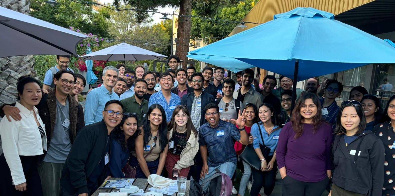 students gathered outside for a happy hour under umbrellas