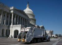 A garbage truck drives by the U.S. Capitol building