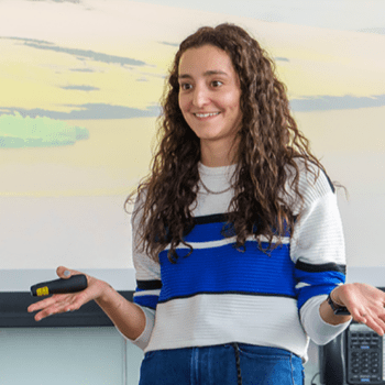 Woman presenting in front of class smiling.