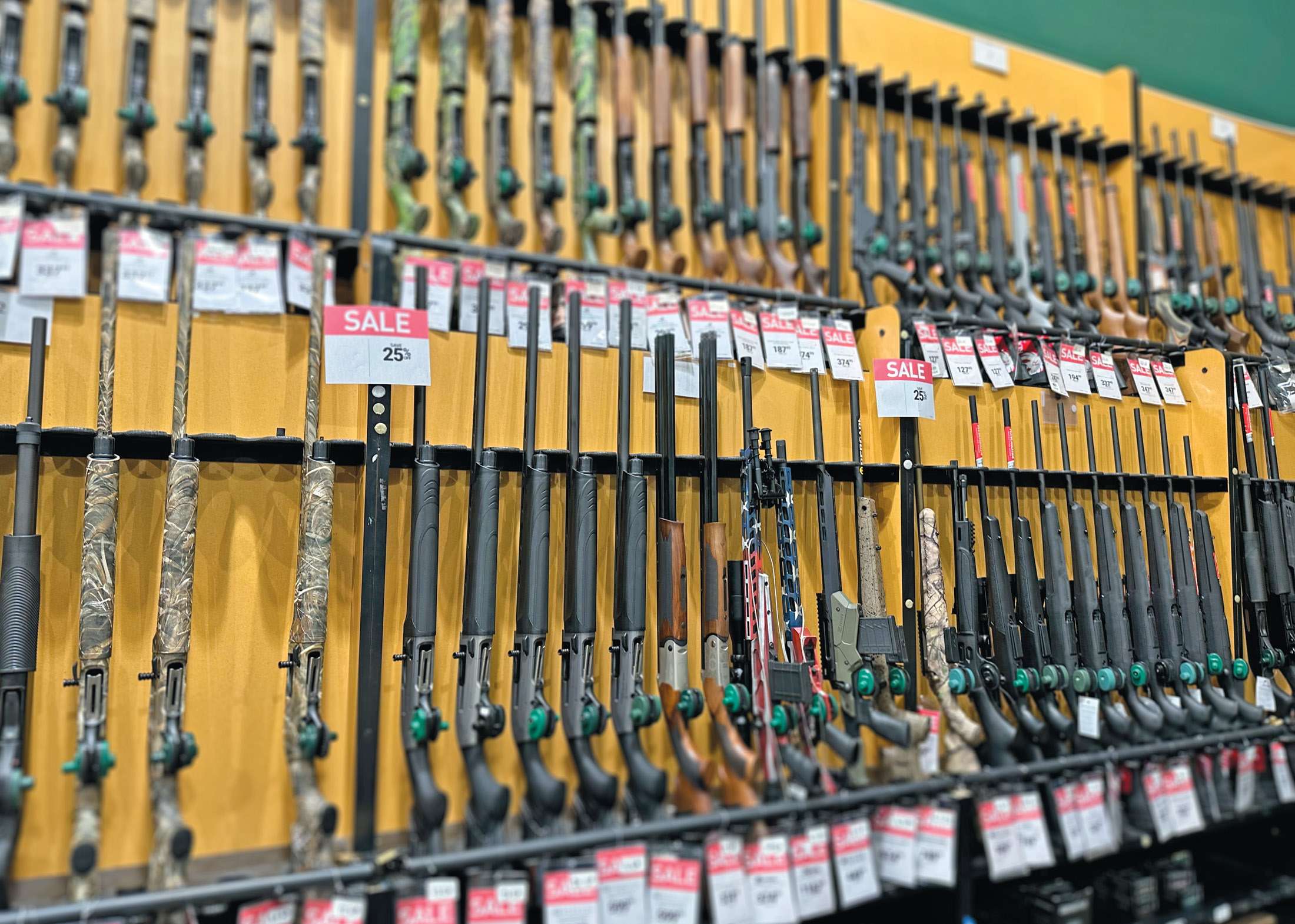 A store display of shotguns with sale stickers